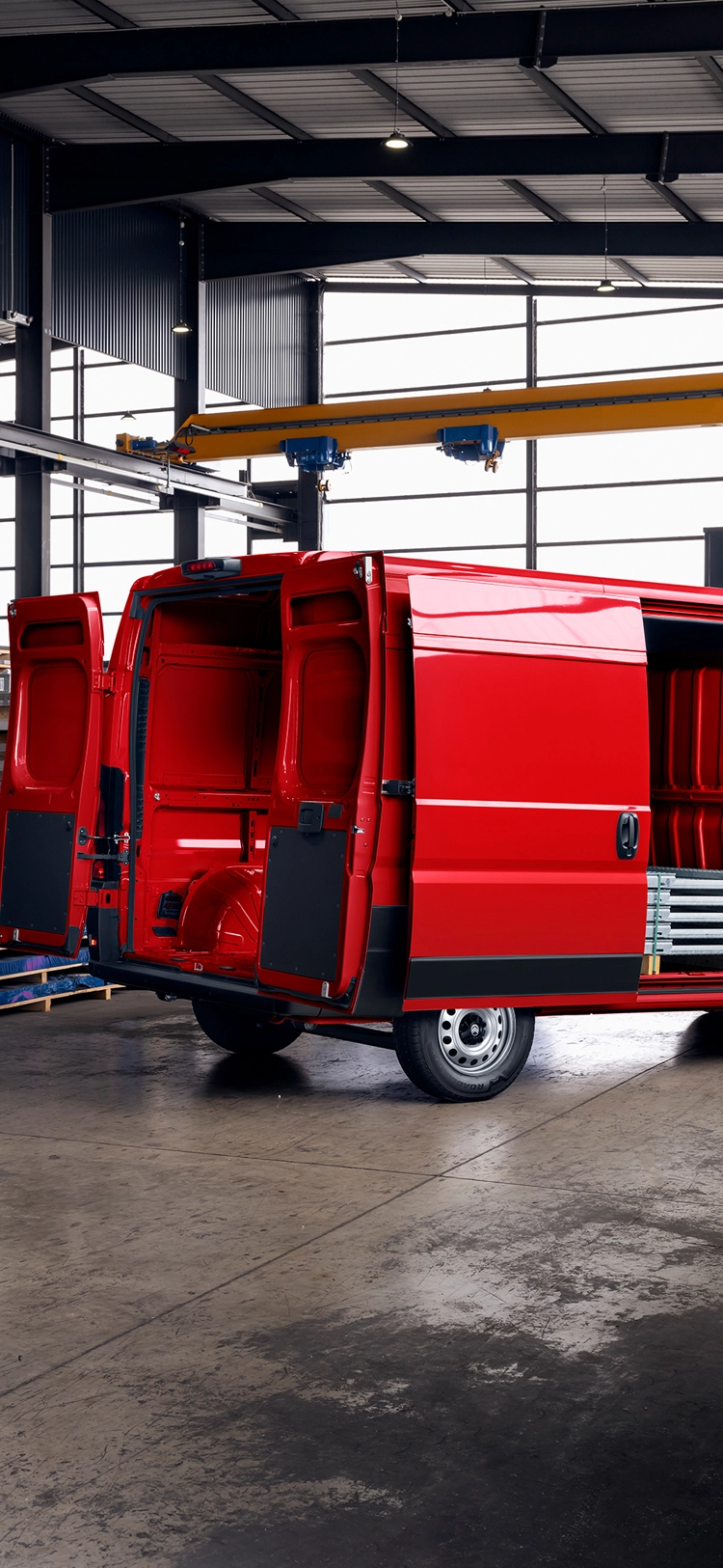 Achteraanzicht van een rode Citroën Jumper met open laadruimte in een magazijn, waarbij laadruimte, duurzaamheid en veelzijdigheid centraal staan.