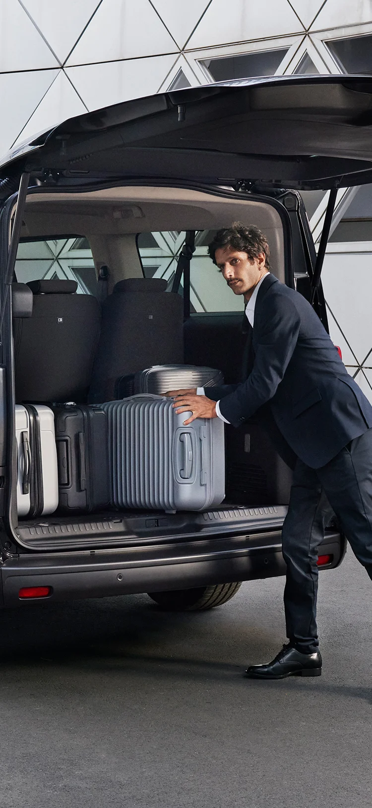 Achterzijde van de Citroën ë‑SpaceTourer met open bagageruimte terwijl meerdere koffers worden ingeladen.